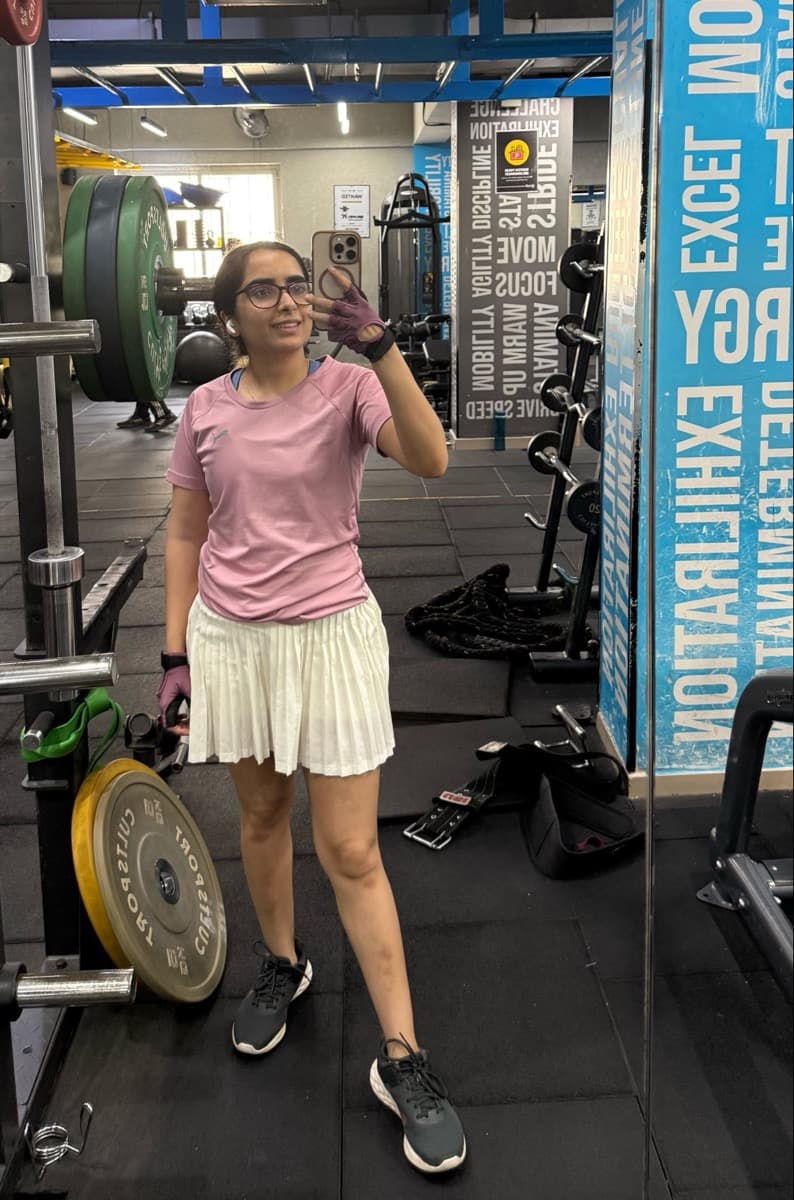 Reet in the gym, mirror selfie in a pink tee